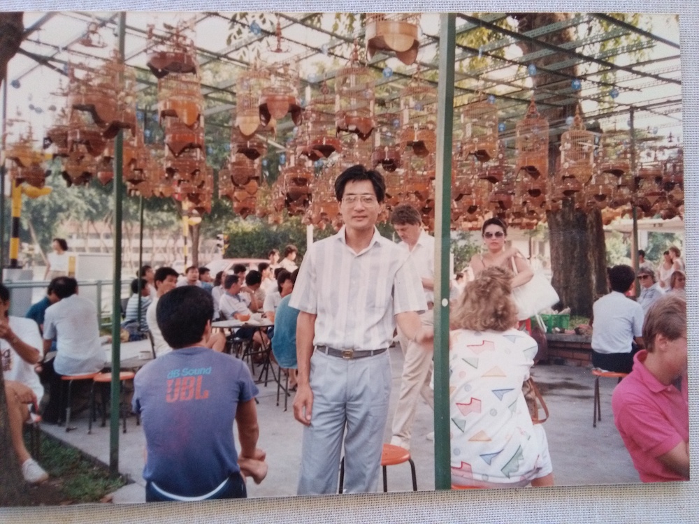 Sous les cages des oiseaux chanteurs, un homme pose sur une photo d'esthétique vintage.