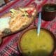 Truite et riz devant soupe avec crudités, un plat présentée sur une nappe coloré.
