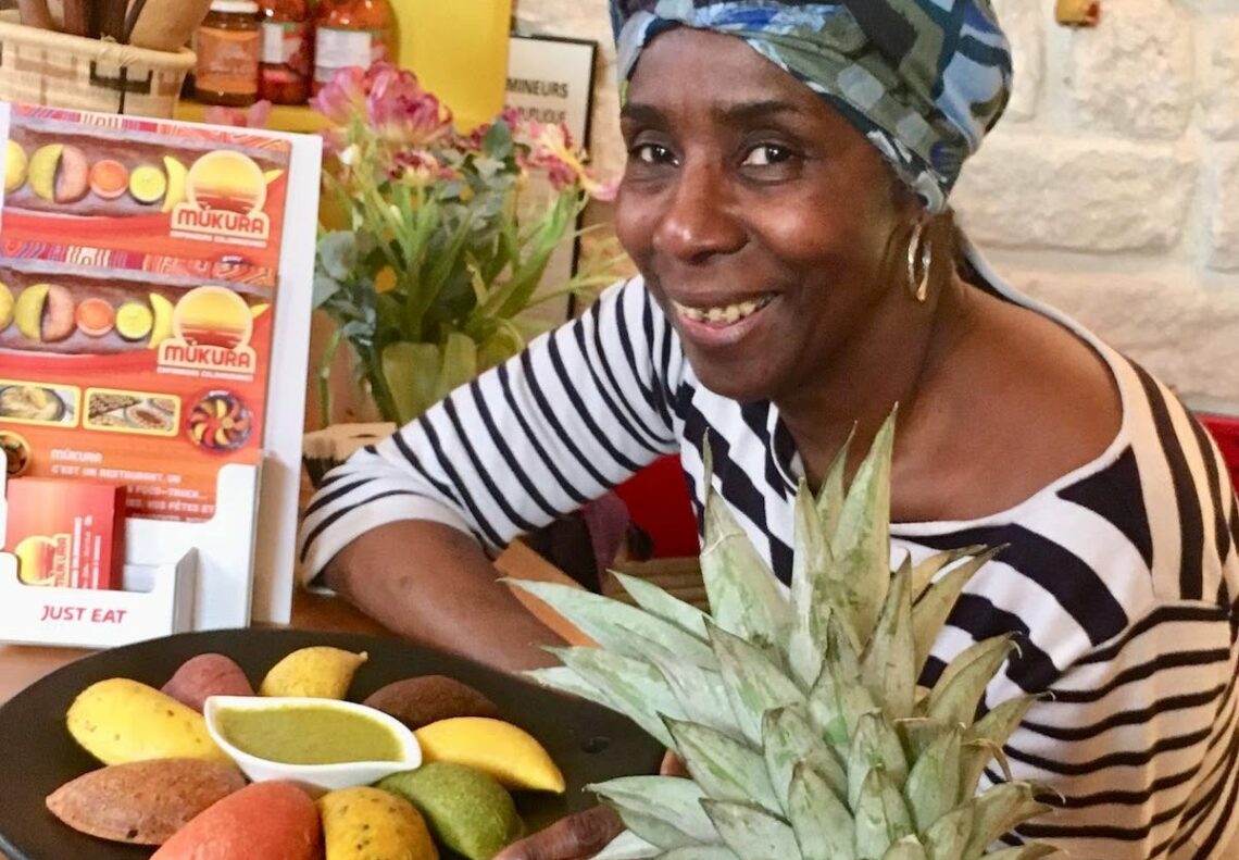 Esperanza Aguilar, souriante, pose à côté d'une assiette d'empanadas colorés.