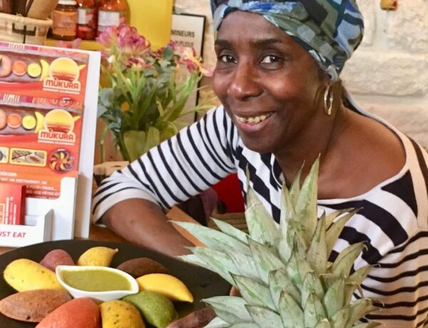 Esperanza Aguilar, souriante, pose à côté d'une assiette d'empanadas colorés.